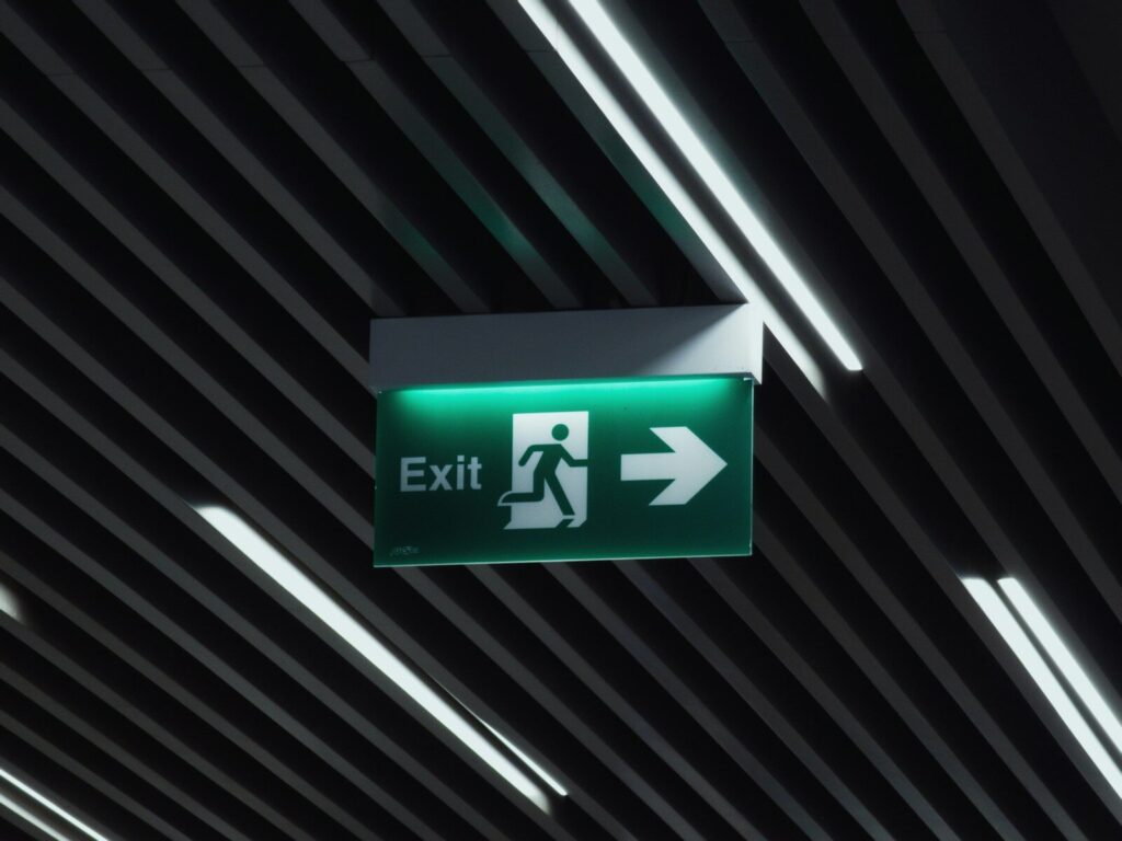 a green emergency exit sign hanging from the ceiling