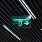a green exit sign hanging from the ceiling